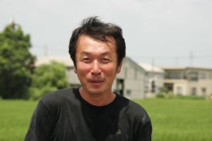 い草畑を背景に宮崎氏